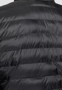 Czarna pikowana kurtka z przeszyciami poziomymi, wykonana z błyszczącego, gładkiego materiału o miękkiej teksturze.