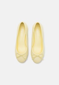 Bailarinas veganas amarillas con una textura suave, punta redonda y un lazo decorativo en la parte delantera. El interior es de un amarillo a juego.