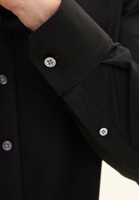 Zwart overhemd met een slim fit, voorzien van een gestructureerde kraag, dubbele mouwknopen met grijze knopen en een gladde, textuurstof.