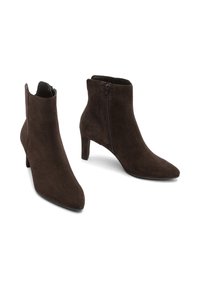 Stivali ankle in suede marrone con punta affusolata, chiusura con zip e un tacco modesto, caratterizzati da una texture liscia e un design elegante.
