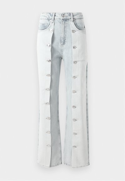 Šviesiai mėlynos džinsinės kelnes su sidabriniais mygtukų akcentais, turinčios platesnius džinsų siluetus ir šonines klostes. Medžiaga turi tekstūruotą apdailą.