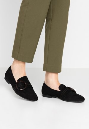 Czarne zamszowe mokasyny z zaokrąglonym noskiem, z szerokim paskiem i okrągłym zapięciem. Teksturowany design z niskim, płaskim obcasem.