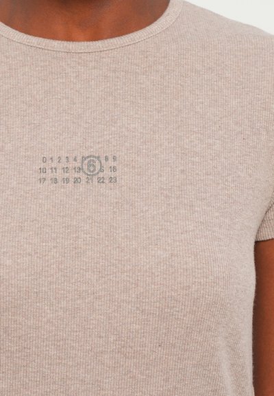 Light beige ribbed t-shirt with a round neckline and short sleeves. Features a printed calendar graphic on the upper left side.