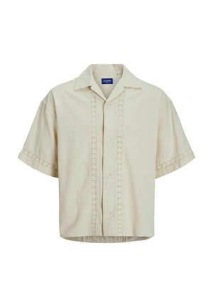 Chemise à manches courtes en lin beige avec un devant boutonné, présentant des détails en œillets le long du centre et des poignets. Ourlet droit.