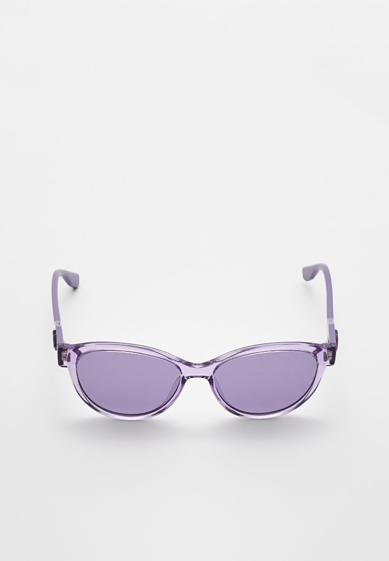 Des lunettes de soleil violettes avec un design ovale élégant, une monture en plastique transparent et des verres teintés. Elles possèdent de fins bras courbés.