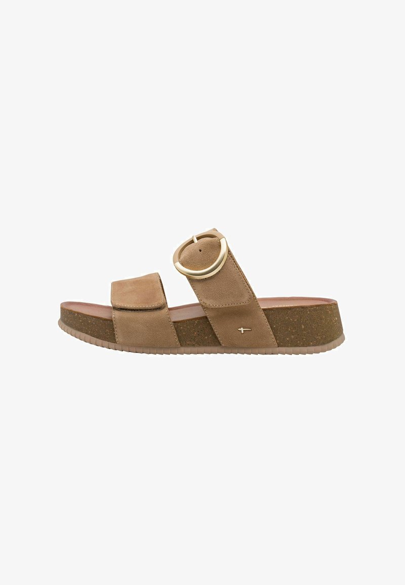 Sandale mule en daim marron avec une large bride et une boucle métallique circulaire. Semelle compensée à texture de liège. Design minimaliste.