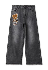 Jeans in denim nero a gamba larga con una toppa a forma di orso sulla coscia sinistra, orlo sfrangiato e design classico a cinque tasche.