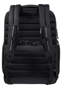 Zaino nero con superficie imbottita e testurizzata, spallacci regolabili e cerniere. Presenta un design elegante e materiale resistente.