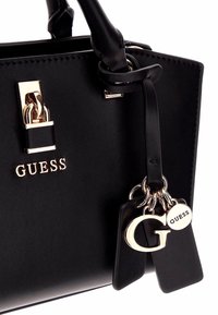 Borsa a mano in pelle nera con accenti dorati, logo dorato e etichette per chiavi. Texture liscia con design strutturato e doppi manici.