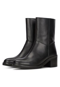 Botas de tobillo de cuero negro con una textura suave, punta redondeada y un tacón bajo en bloque. Presenta costuras sutiles a lo largo de las costuras.