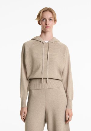 Beige gebreide hoodie met ribbelmouwen en onderkant, voorzien van een capuchon met trekkoord en een getailleerde taille, gecombineerd met bijpassende beige broek.