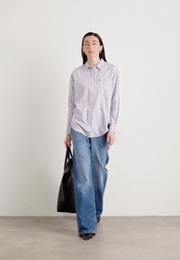 Light purple checkered button-up shirt, loose blue jeans, and black tote bag. Smooth fabric with long sleeves, relaxed fit, and casual style.