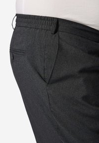 Šedé texturované kalhoty s elastickým pasem, boční kapsou a přizpůsobeným střihem, které zdůrazňují funkční design a pohodlí pohybu.