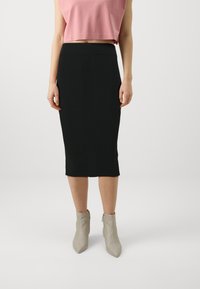 Fekete bordázott ceruza szoknya geometrikus textúrával és magas derékrésszel, világosszürke hegyes bokacsizmával párosítva.