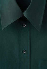 Dark green shirt featuring a sharp collar, long buttoned placket with black buttons, and a pocket on the left side. Smooth fabric texture.