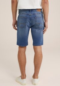 Denim kratke hlače v srednji modri barvi, z vidnimi šivi, dvema zadnjima žepoma in usnjenim oznako na pasu. Ravno rez.