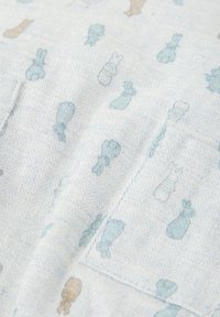 Tela azul claro con una textura de espiga, que presenta pequeños patrones de conejos y otros animales en tonos suaves de azul y beige.