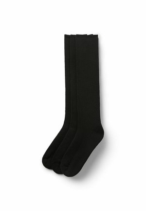 Drei Paar schlichte schwarze knielange Socken ordentlich auf einem weißen Hintergrund gestapelt.