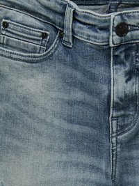 Svijetloplave traperice s klasičnim dizajnom od pet džepova, metalnim zatvaranjem na gumbe i suptilnim izbleđenjem na tkanini.