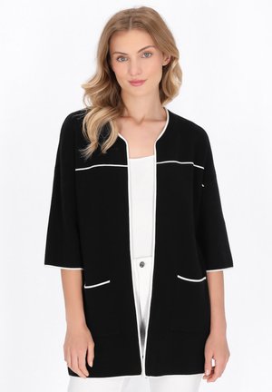 Schwarze Strickjacke mit halben Ärmeln, weißen Besätzen, zweivorderen Taschen und lockerer Passform. Hergestellt aus weichem Stoff und verfügt über ein sauberes Design.