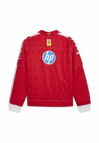 Giacca da corsa rossa con polsini bianchi, logo Ferrari in alto, grande logo blu HP al centro della schiena e loghi bianchi degli sponsor sulle maniche.