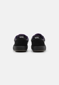 Černé boty Vans s svrchním materiálem z semiše a síťoviny, fialovým podšívkou a bílým logem. Mají nízký design a gumovou podrážku.