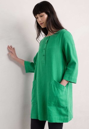 Robe en lin verte avec une coupe ample, des manches trois-quarts, un col arrondi, une patte de boutonnage et deux poches latérales. Tissu texturé.