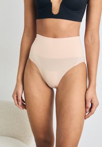 Beige high-waisted briefs made from smooth, lightweight fabric, featuring a seamless design and slight sheerness at the leg openings.