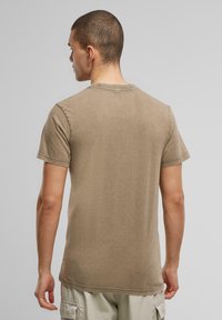 Khaki bomulds-t-shirt med rund hals og korte ærmer, med en let tekstureret overflade og synlige sømme langs kanterne.