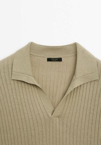 Pull en maille côtelée beige avec un large col et une ouverture en V, montrant une étiquette de marque noire à l'intérieur de l'encolure.