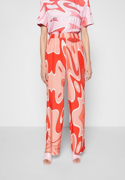 Calças largas com padrão em vermelho e rosa, apresentando desenhos de ondas abstratas, feitas de tecido suave, com um cós elástico.
