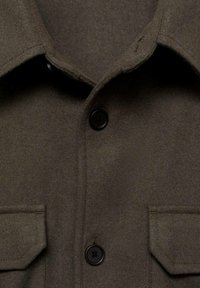 Brown wool blend shirt jacket with a collared neckline, black buttons, and two front pockets. Soft texture, straight cut design.