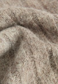 Tessuto a maglia beige testurizzato con motivi variati, che mette in mostra fibre sottili e un aspetto morbido, tessuto densamente per calore e comfort.