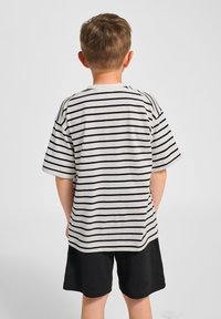 Randig T-shirt i vitt med svarta horisontella ränder, korta ärmar, rund halsringning, kombinerad med svarta shorts, sedd bakifrån.