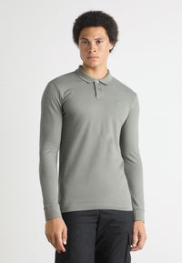 Langarm polo shirt in gedempt groen katoen met een klassieke kraag, voorzien van een knoopsluiting en een subtiele logodetail op de borst.