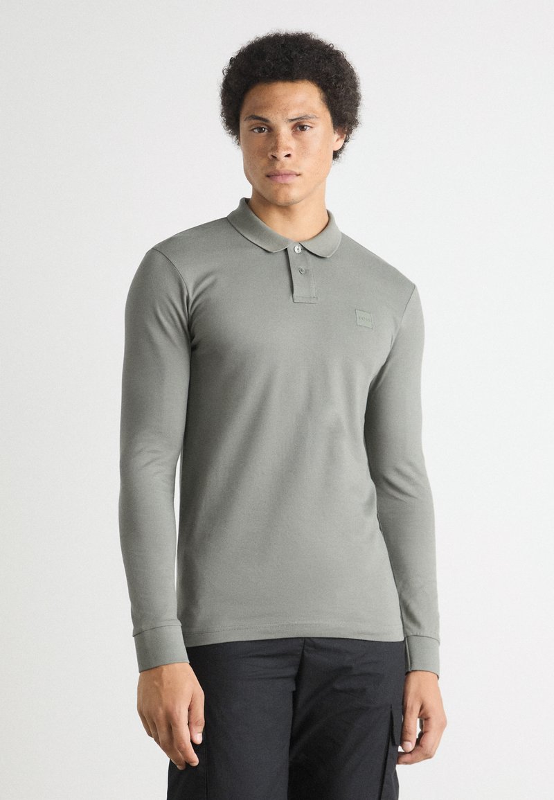 Langarm polo shirt in gedempt groen katoen met een klassieke kraag, voorzien van een knoopsluiting en een subtiele logodetail op de borst.