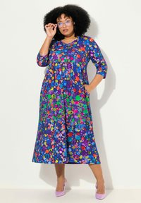 Vestido de estampado floral multicolor con mangas tres cuartos, escote en V y bolsillos. Hecho de una tela suave con una silueta suelta y fluida.