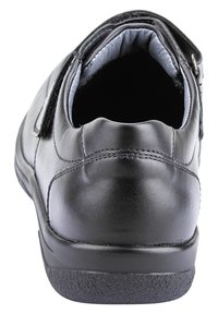 Scarpa in pelle nera con retro arrotondato e tacco basso. Foderatura interna morbida visibile, dotata di suola in gomma testurizzata e cinturino regolabile.