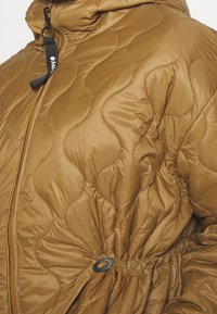 Chaqueta acolchada marrón con capucha, que presenta un cordón negro, cierre de cremallera y cintura ajustada. Tela suave con un acabado brillante.