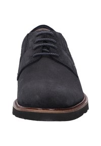 Chaussure habillée en suède noir avec un bout arrondi, un laçage, et une semelle épaisse en caoutchouc avec un accent marron le long du bord.