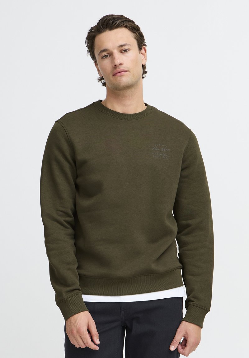 Olijfgroene sweatshirt met een ronde halslijn, lange mouwen en geribde manchetten. Heeft een subtiele tekstontwerp op de borst. Zacht textuur van de stof.