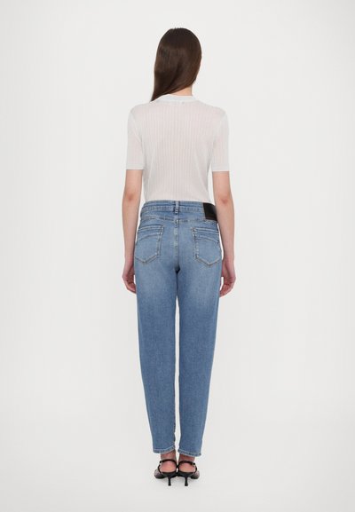 Ανοιχτό μπλε ψηλόμεσα τζιν με χαλαρή εφαρμογή, χαρακτηριστικά ίσια πόδια, πίσω τσέπες και μαύρη ετικέτα στη μέση.