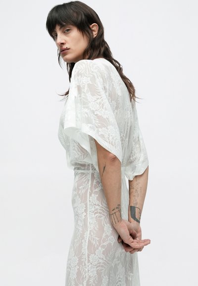 Pitskleit lillemustriga, lühikeste lahtiste varrukatega ja poolläbipaistva valge tekstuuriga. Disain on pahkluuni pikk ja taljest liibuv.