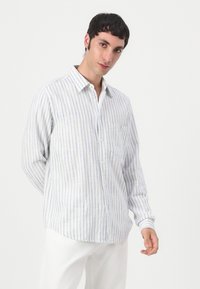 Leichte, langärmlige, knöpfbare Bluse in Weiß mit feinen blauen Streifen. Verfügt über eine Brusttasche und einen klassischen Kragen, hergestellt aus atmungsaktivem Stoff.
