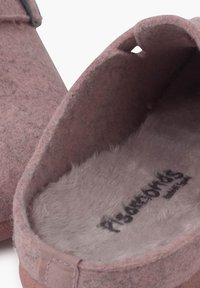 Pantofole di feltro rosa con una superficie testurizzata, morbido rivestimento in pelliccia sintetica e un'apertura circolare sul lato. Include il logo del marchio sulla soletta.