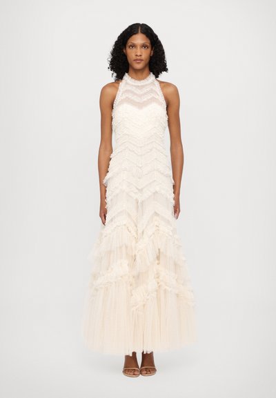 Abito da sera maxi in tessuto crema con ruches a strati, collo all'americana, sovrapposizioni trasparenti e una silhouette fluida. Sandali con tacco semplici.