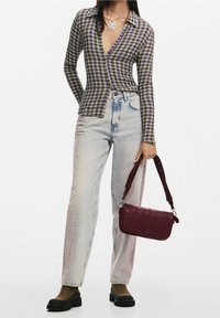 Chemise à manches longues à motif check dans des tons de violet et de vert, associée à un jean délavé avec un design dégradé, et un sac à main bordeaux.