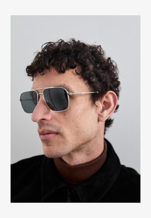 Óculos de sol com uma armação de metal prata, lentes escuras e formato retangular. As hastes apresentam pequenos detalhes cilíndricos.