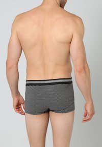Cuecas de tronco riscado em preto e cinza com uma cintura elástica preta e linhas horizontais subtis, projetadas para uma silhueta ajustada.