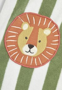 Broderet løve-design i orange og beige på en grøn og hvid stribet baggrund. Har en blød tekstur og rund form.
